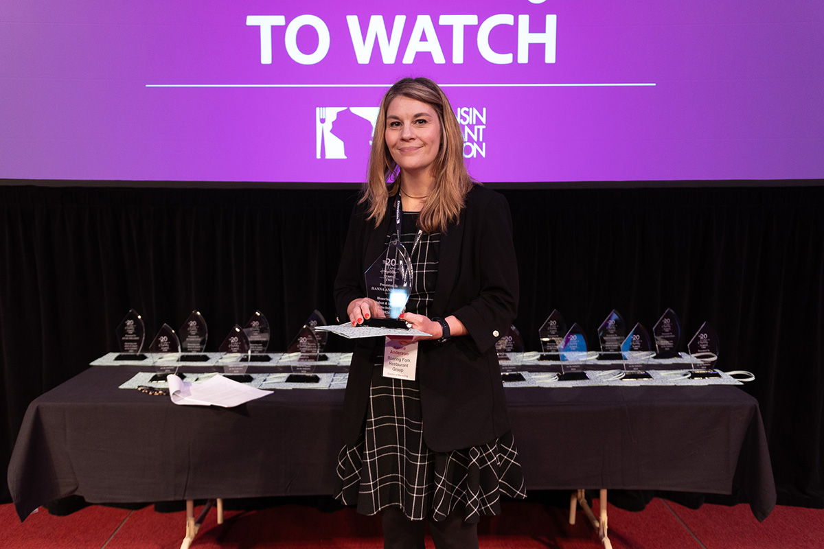 Roaring ForkRestaurant Group's Director of Marketing, Hanna Anderson, on stage accepting an award for being named one of the Top 20 Women in Hospitality to Watch by the Wisconsin Restaurant Association in 2024.